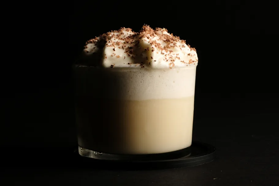 Cremiger Kaffee mit Schaum auf dunklem Hintergrund.