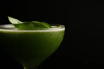 Grüner Cocktail mit Blättern auf dunklem Hintergrund.