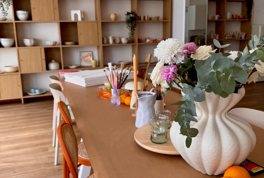 Blumenarrangement auf Holztisch mit Regalen.