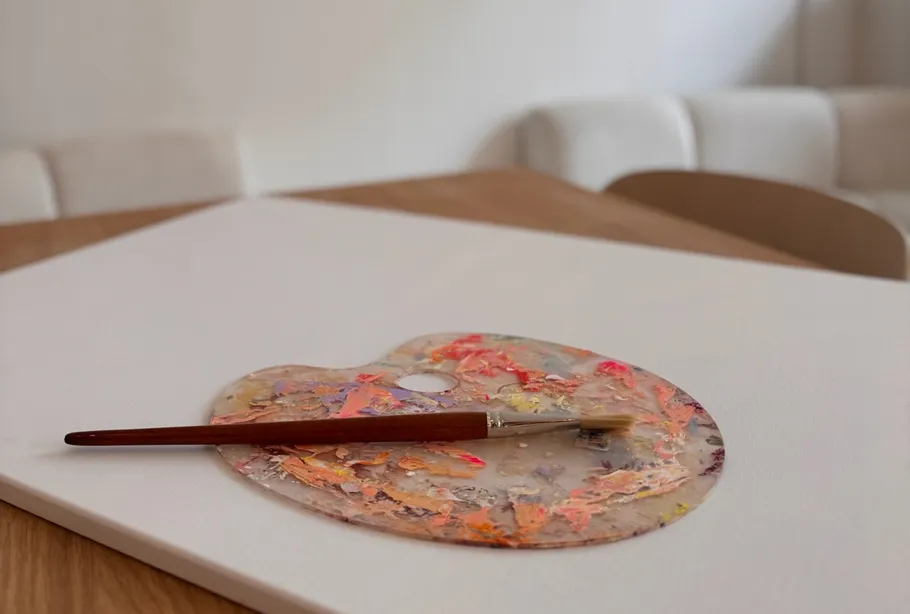 Paintbrush on palette on white canvas.