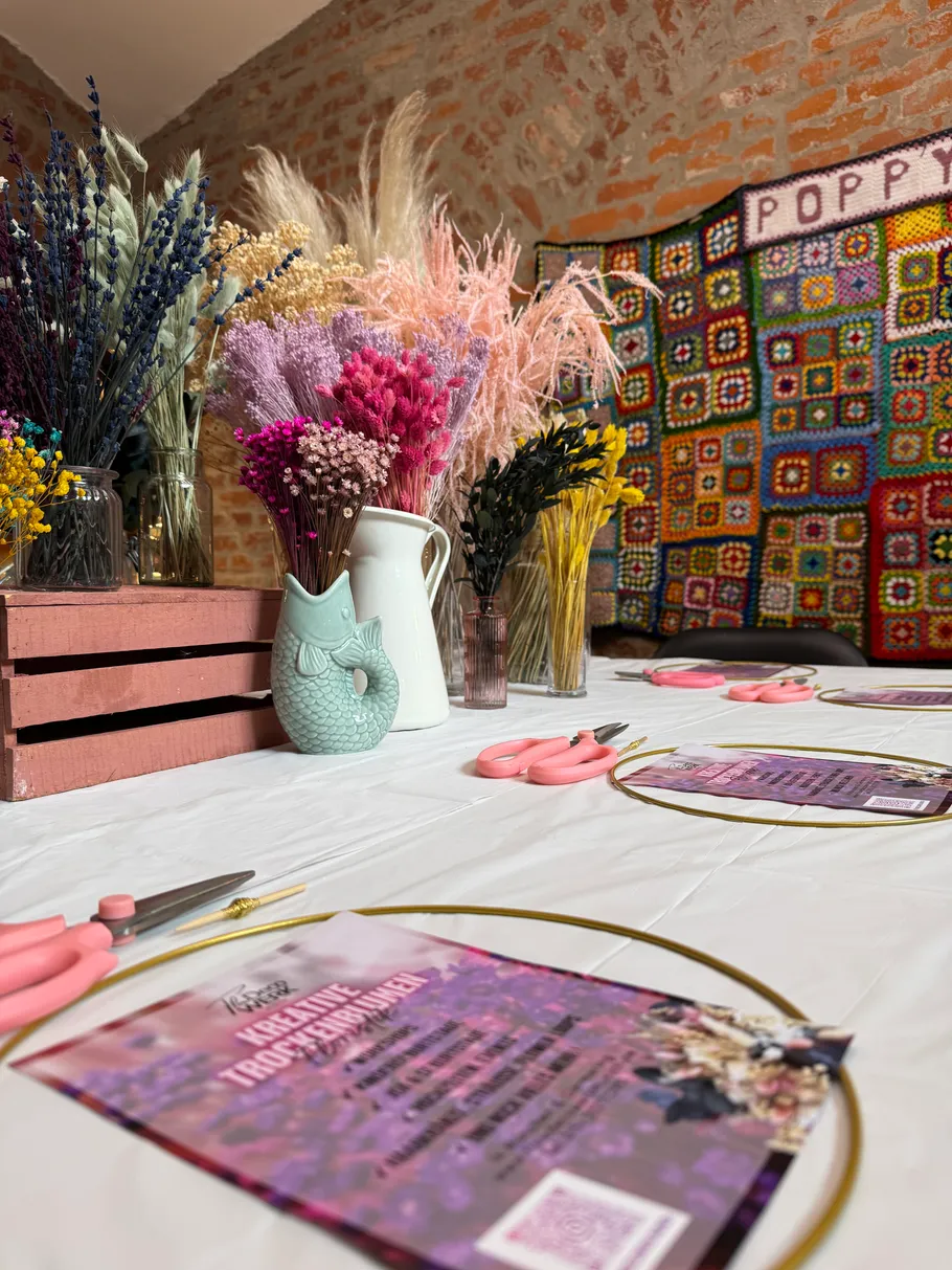 Craft table with dried flowers, scissors, flyers.