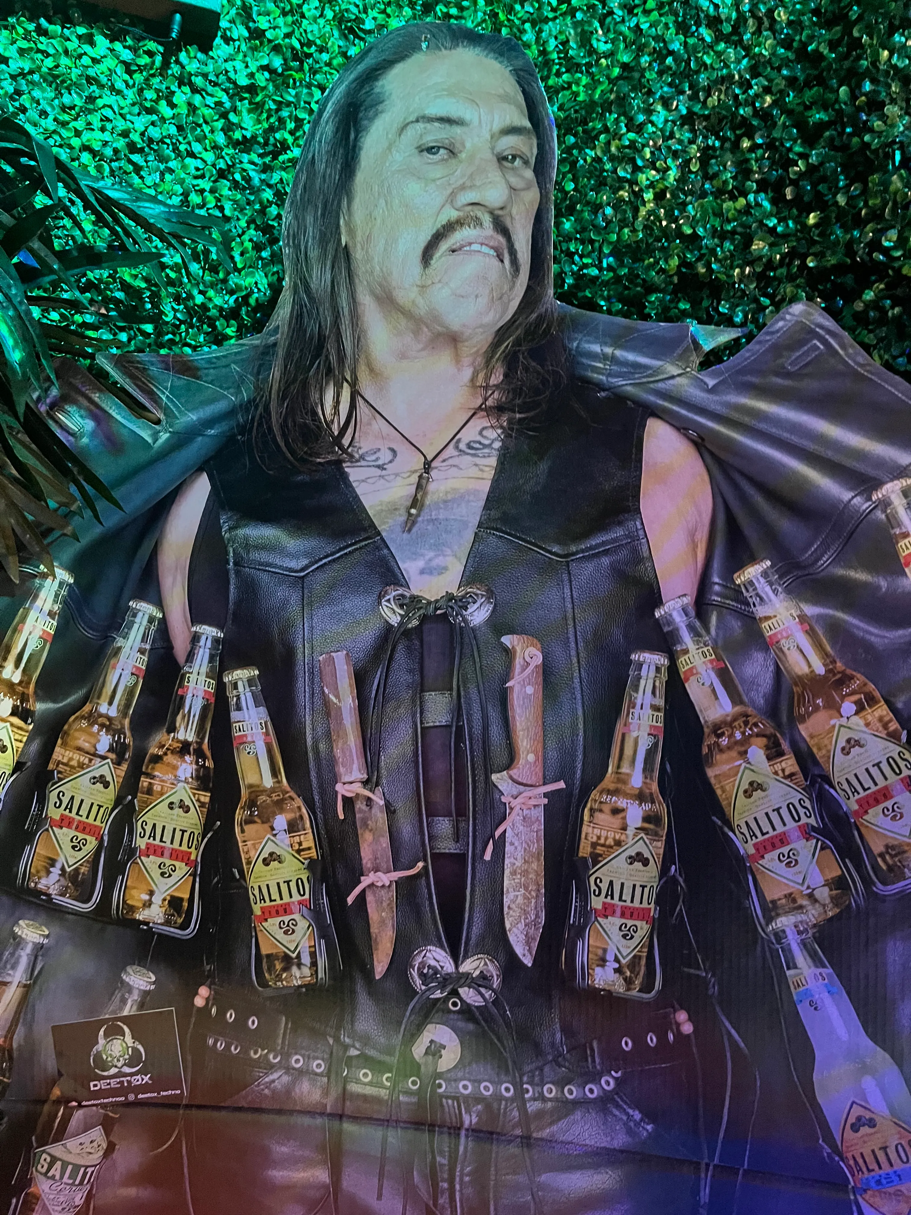 Man in leather vest holding beer bottles.