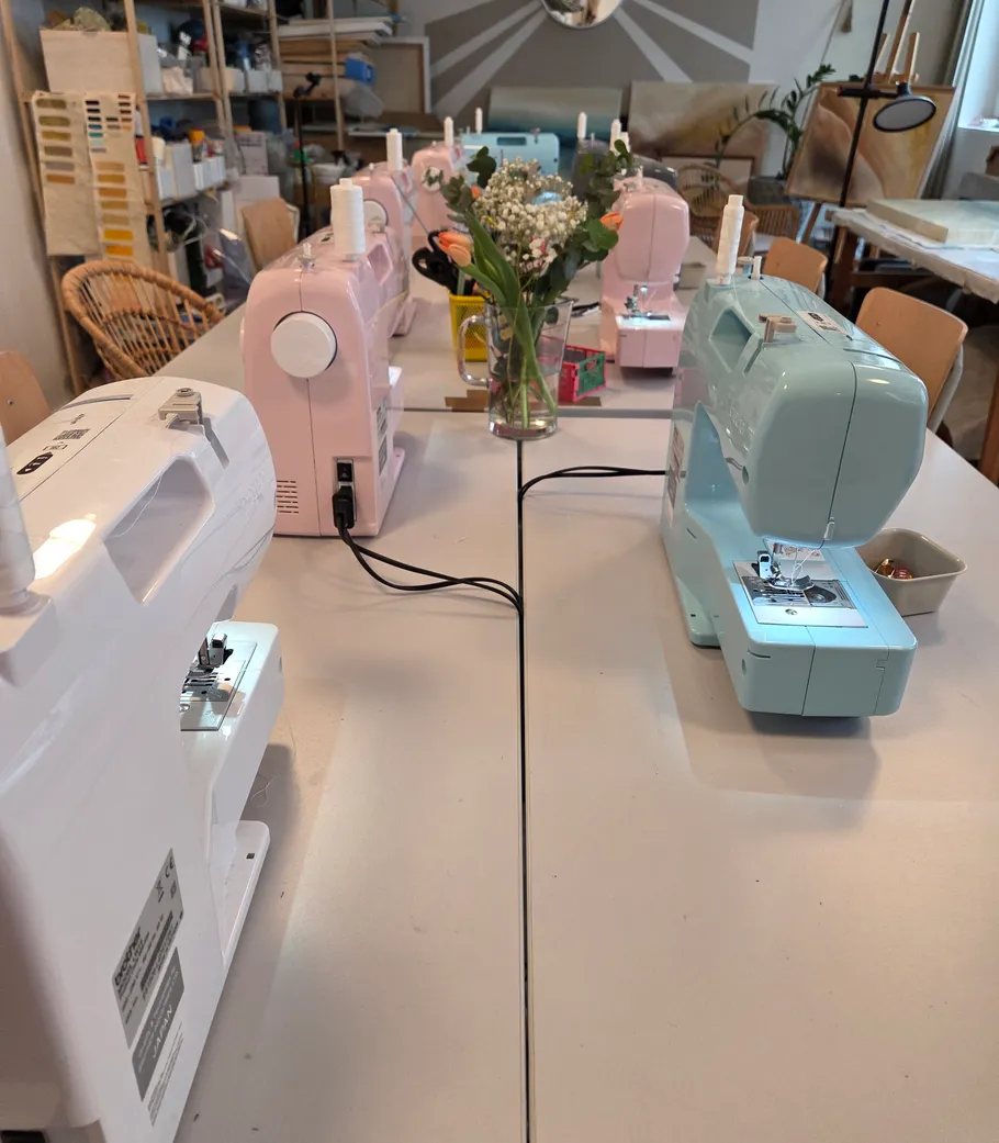 Sewing machines aligned on a workshop table.