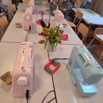 Nähmaschinen auf Tischen in einer Werkstatt.