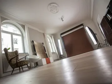 Fotostudio mit Stuhl, Lichtern und Hintergrund.