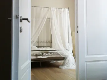 Ein Bett mit zarten Vorhängen steht im Schlafzimmer.