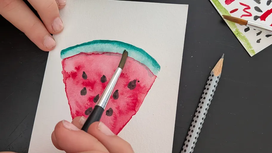 Hand painting watermelon slice on paper.