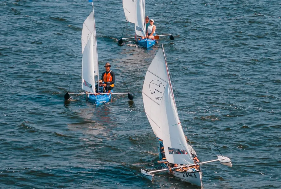 Three small sailboats sailing on a lake.
