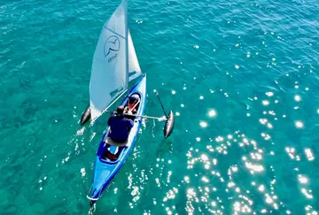 Person segelt im Kajak auf klarem blauen Wasser.