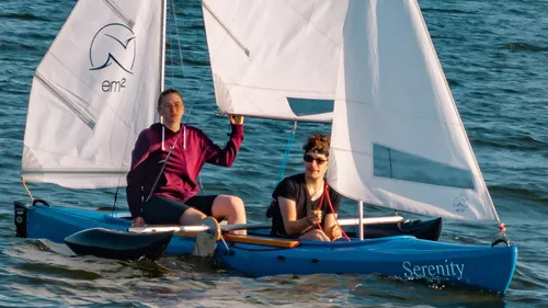 Zwei Personen segeln ein blaues Boot auf Wasser.