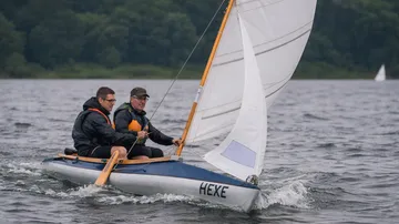 Zwei Personen segeln auf einem kleinen Boot.