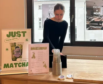 Person preparing drinks at matcha stand indoors.