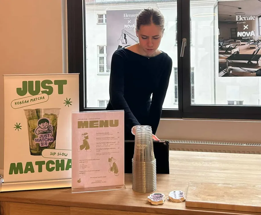 Person preparing drinks at matcha stand indoors.