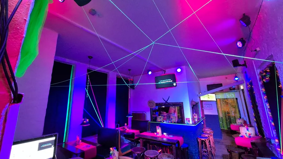 Bunte Bar mit Neonlichtern und Fadendekoration.