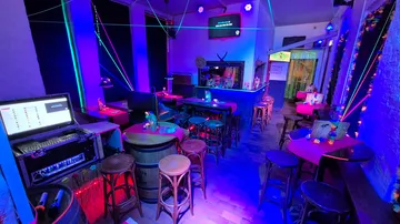 Bunte Karaoke-Bar mit Neonlichtern und Tischen.