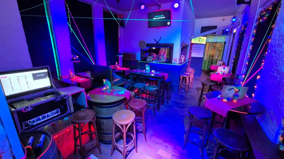 Colorful karaoke bar with neon lights and tables.