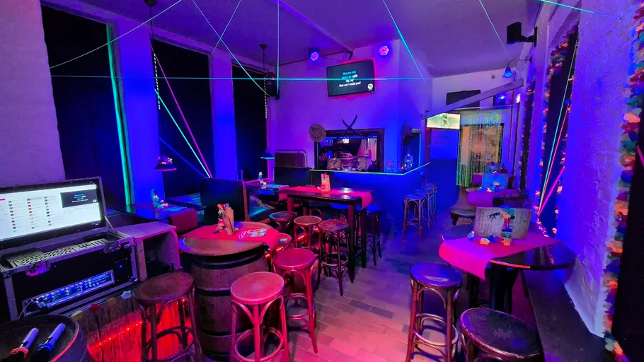 Neonbeleuchtete Bar mit Tischen und Stühlen.