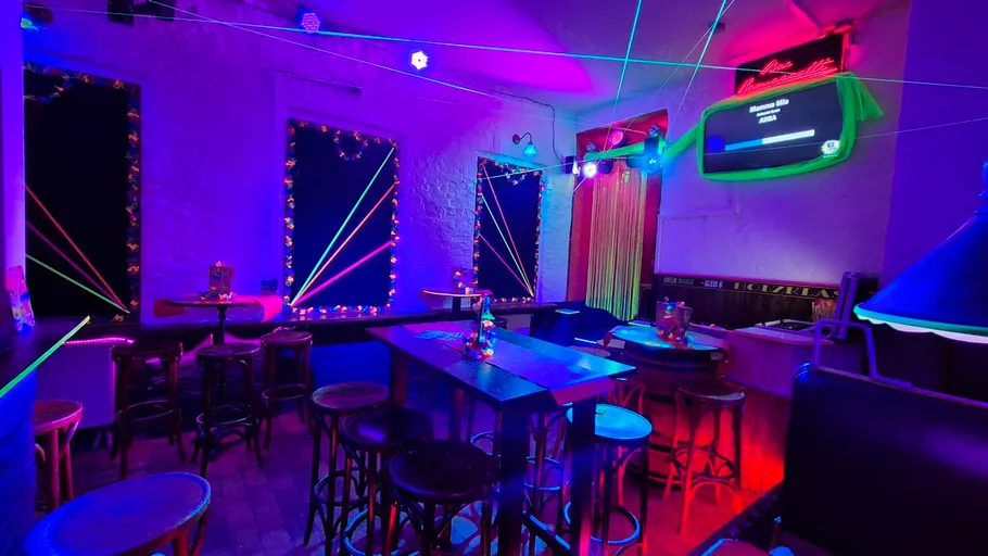 Neonbeleuchtete Bar mit bunten Dekorationen und Sitzgelegenheiten.