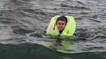 Person schwimmt im Wasser mit Schwimmweste.
