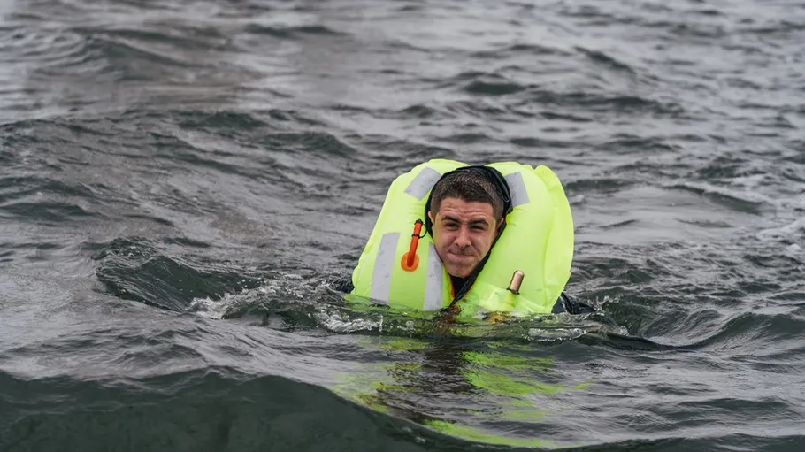 Man wearing life jacket in rough sea.