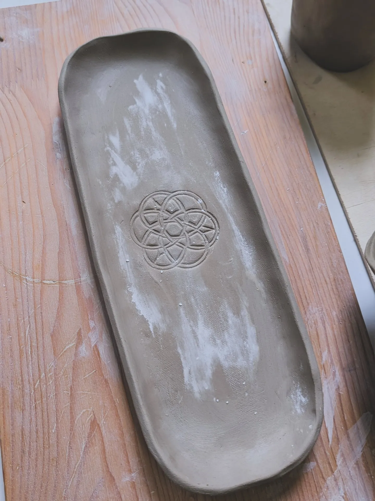 Ton-Tablett mit geprägtem Muster auf Tisch.