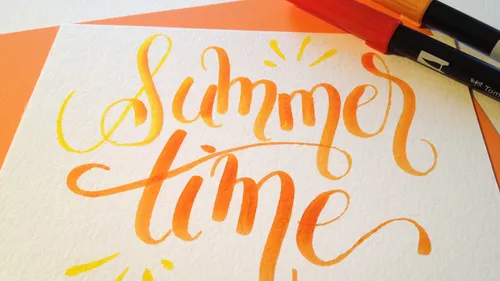 Kalligrafie mit "Summer time," Stifte daneben.