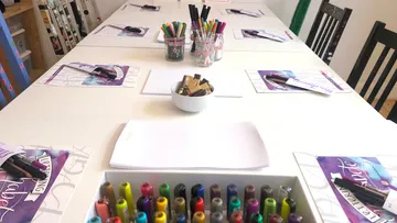 Tisch mit Markern und Kalligrafiezubehör.