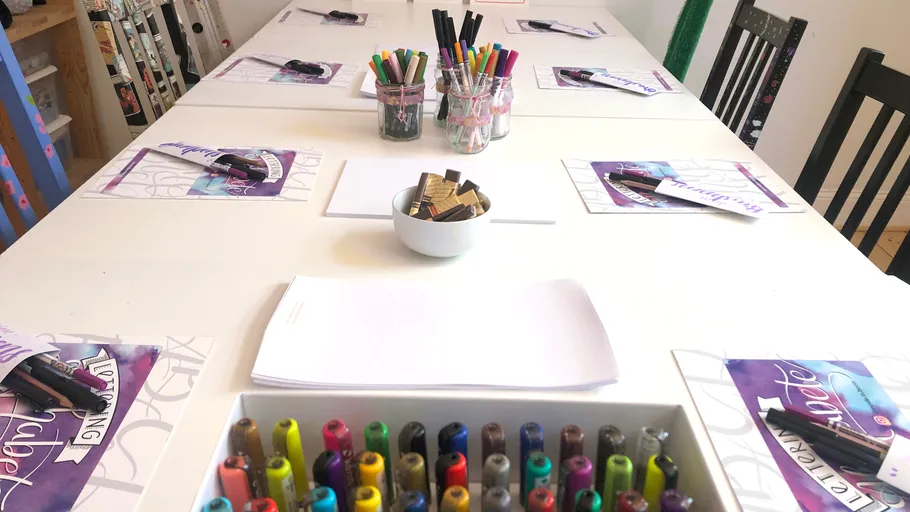 Table with markers and calligraphy supplies.