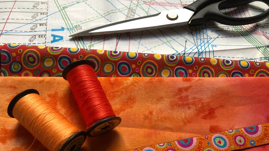 Scissors, thread, and fabric on pattern paper.