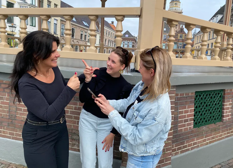 Three women conversing and smiling outdoors.