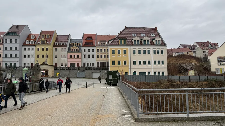 People walking on pathway with colorful buildings.