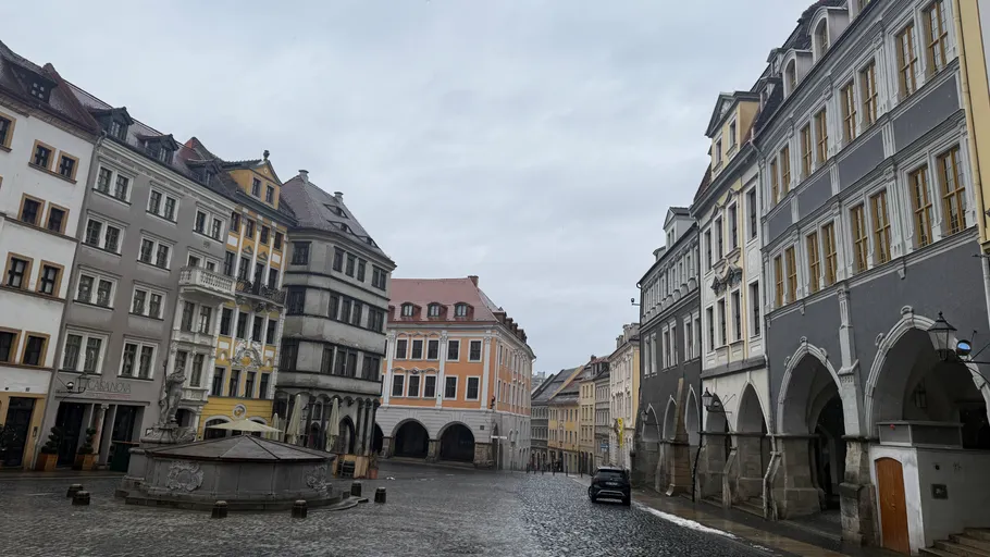 Kopfsteinpflasterplatz mit historischen Gebäuden und Brunnen.