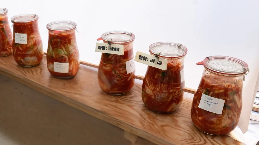 Jars of kimchi on a wooden shelf.