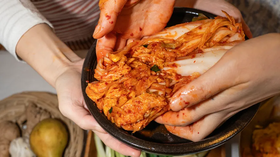 Hände bereiten Kimchi in einer Küche zu.
