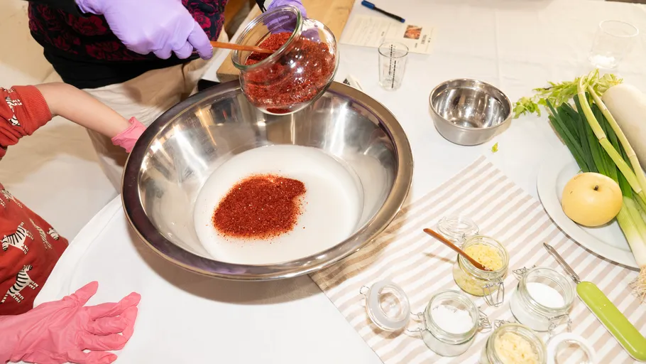 Hands pouring spices into a metal bowl.
