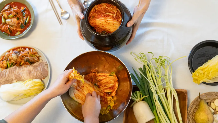 People making kimchi at a table.