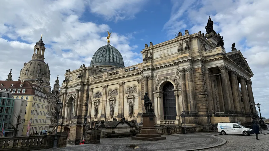 Historic building with dome and sculptures in city.