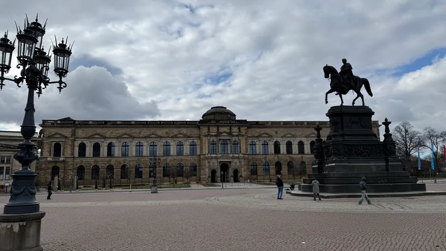 Equestrian statue and historic building under cloudy sky.