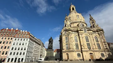 Statue vor großer barocker Kirche.