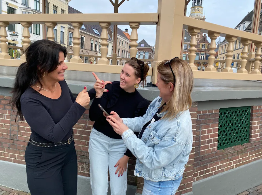 Three women talking and smiling outdoors.
