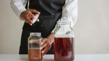 Person verschließt Glas mit Getränk auf Tisch.