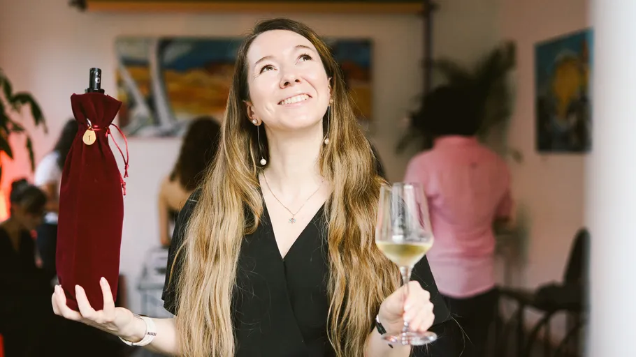 Woman holding wine bottle and glass indoors.