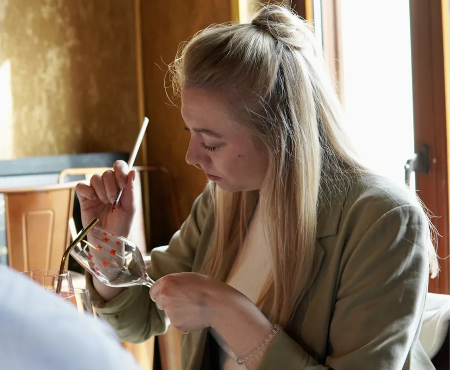 Woman paints a wine glass indoors.