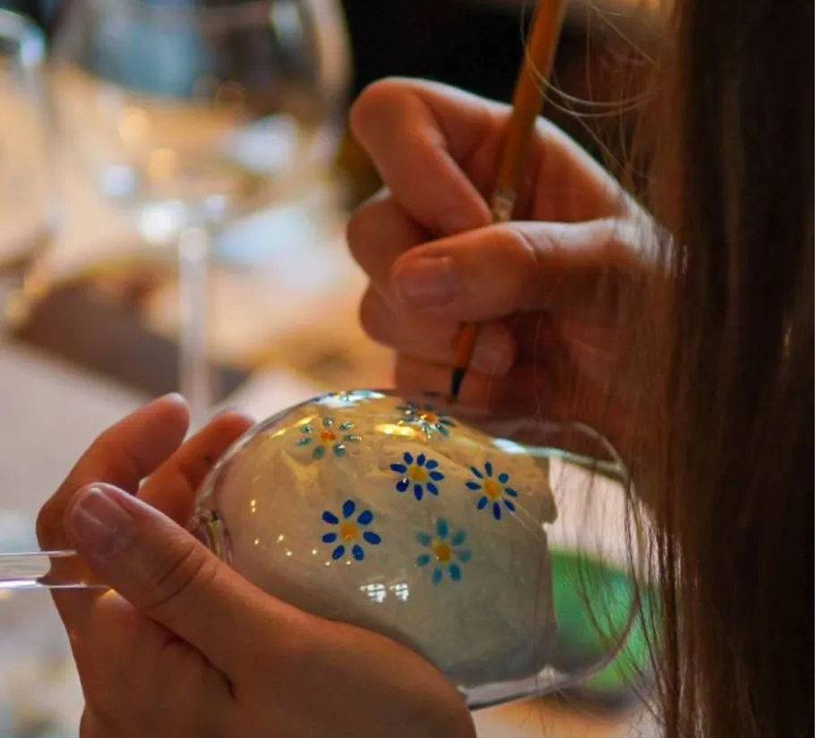 Hand malt blaue Blumen auf ein Glas.