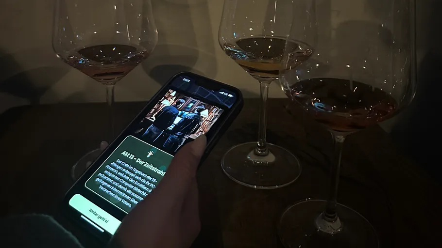 Hand holding phone near three wine glasses.