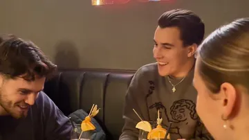 Drei Personen lachen in einem dunklen Restaurant.