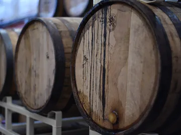 Fässer lagern, Flüssigkeit tropft, Umgebung ist eine Wein- oder Lagerhalle.