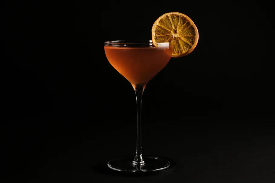 Cocktail with orange slice, black background.