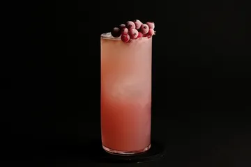 Rosa Cocktail mit gefrorenen Beeren obenauf.