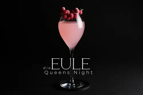 Pink cocktail with berries in dark setting.